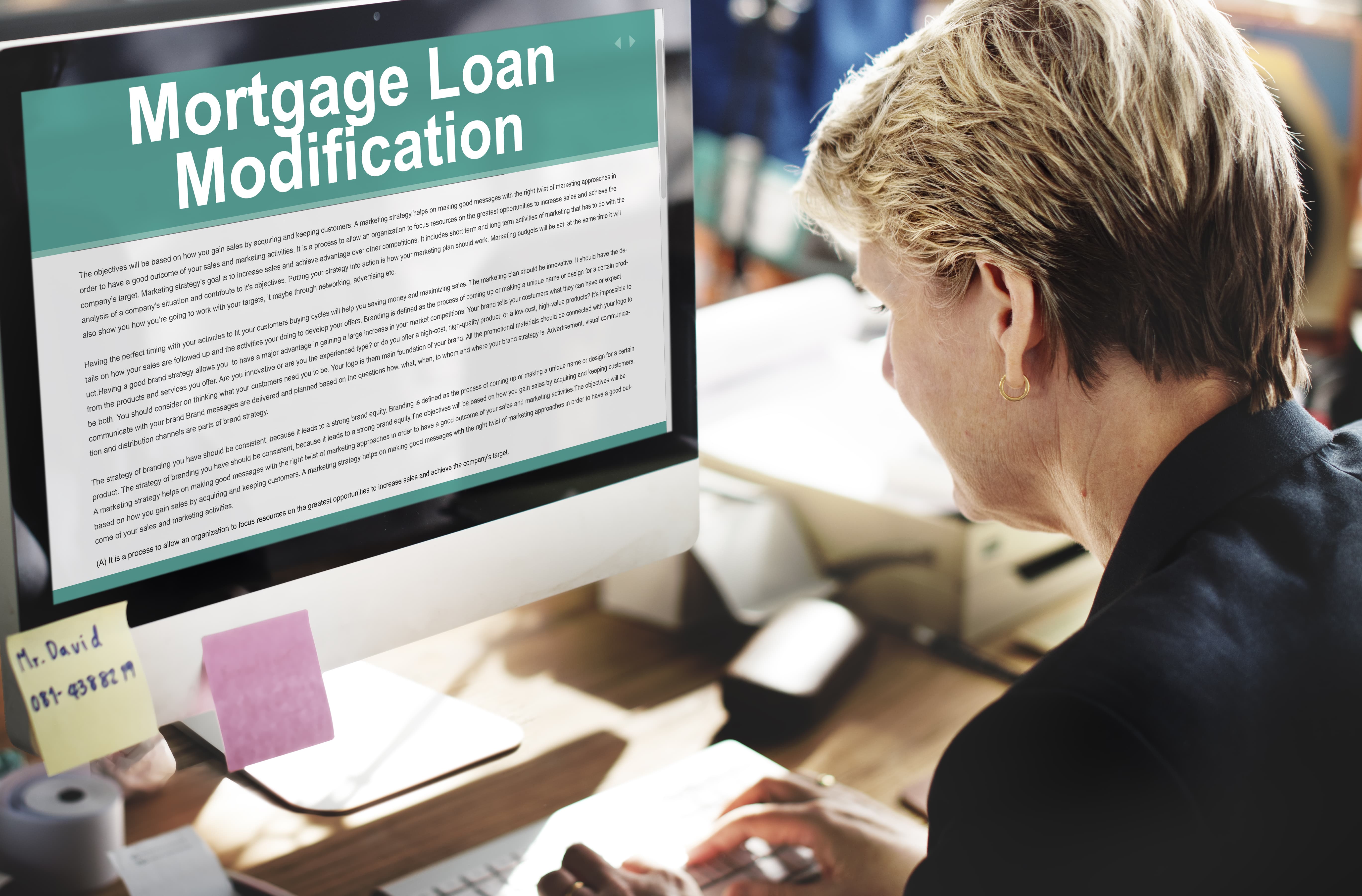 Woman watching on her monitor the mortgage loan modification form.