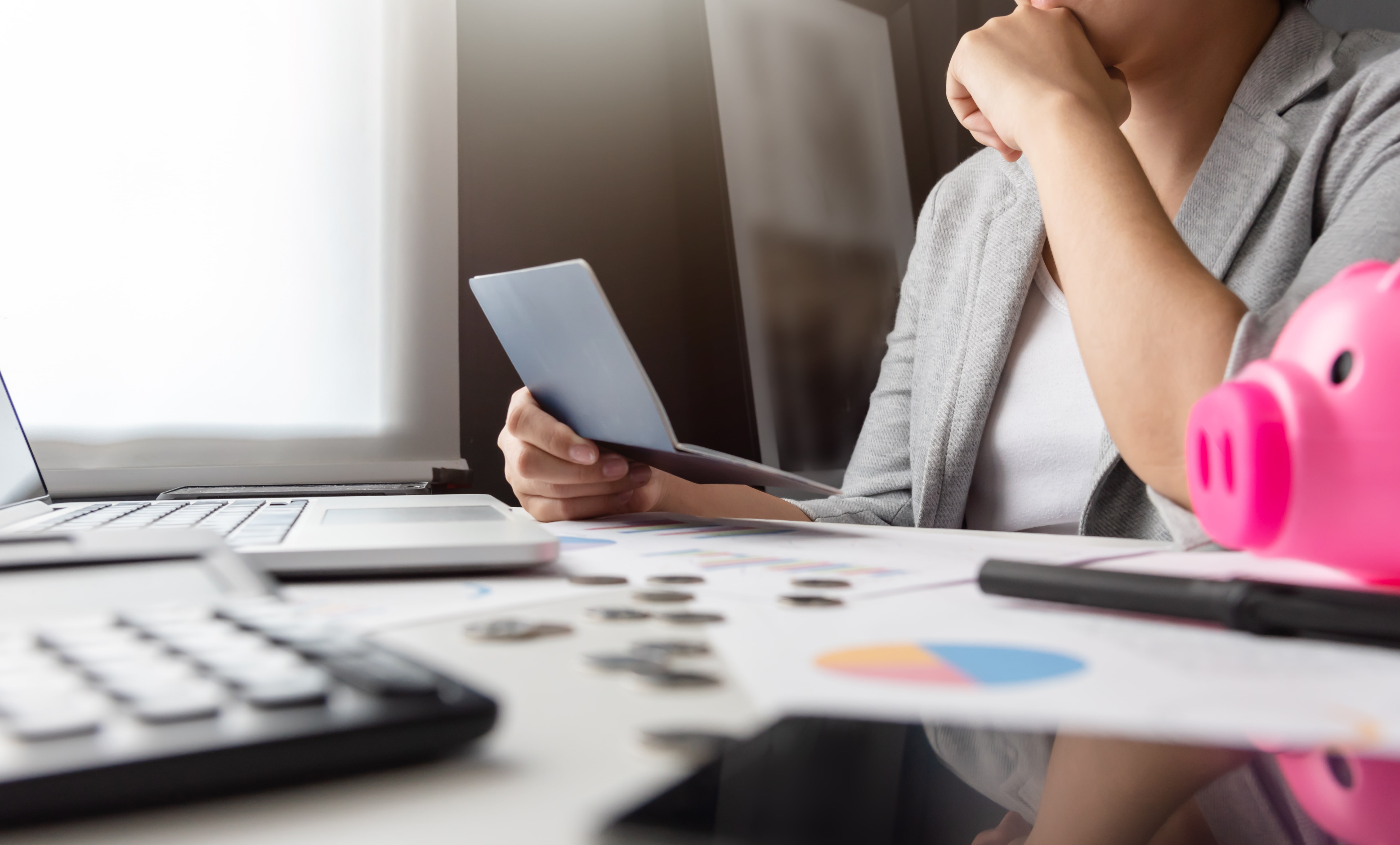 Woman holding her passbook is stressed over her unpaid debts.