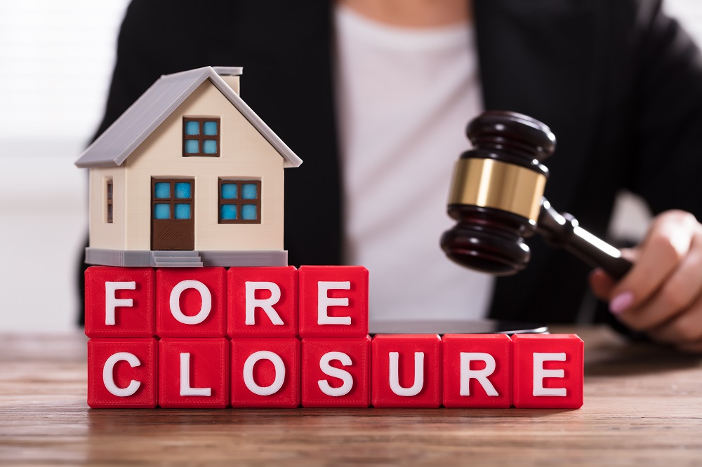 Foreclosure concept with toy house and lawyer with gavel.
